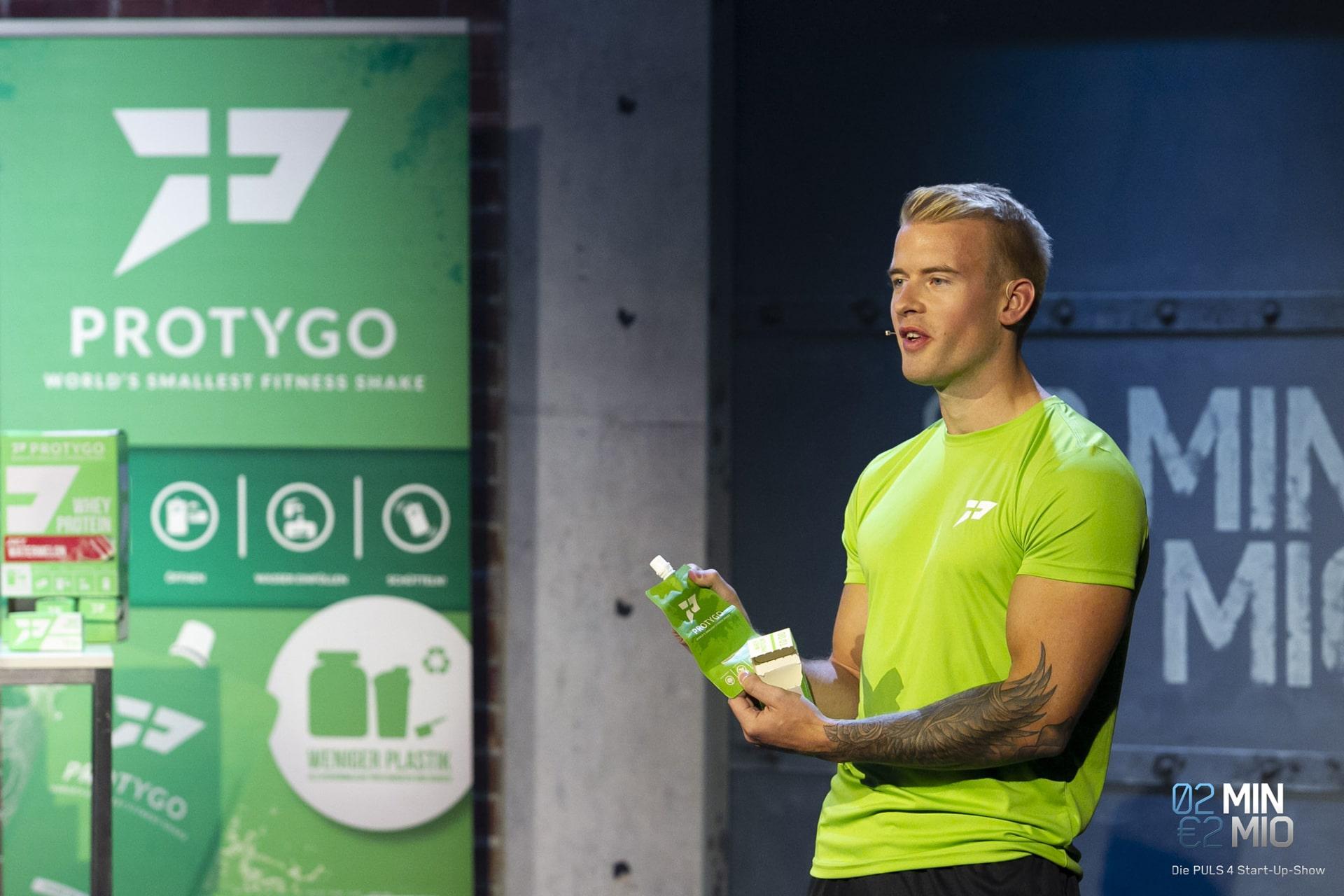 Marco Perner zeigt sein Produkt Protygo bei der Puls 4 Show 2 Minuten 2 Millionen, stehend auf der Bühne und im Gespräch mit den Investoren.
